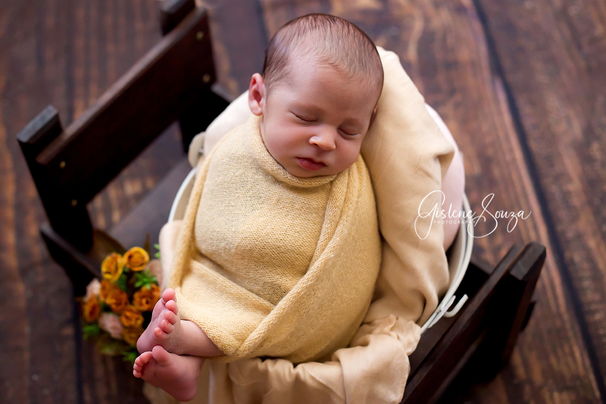 Ensaio de newbor posicionado no prop com piso de madeira. Realizado em Belo Horizonte.