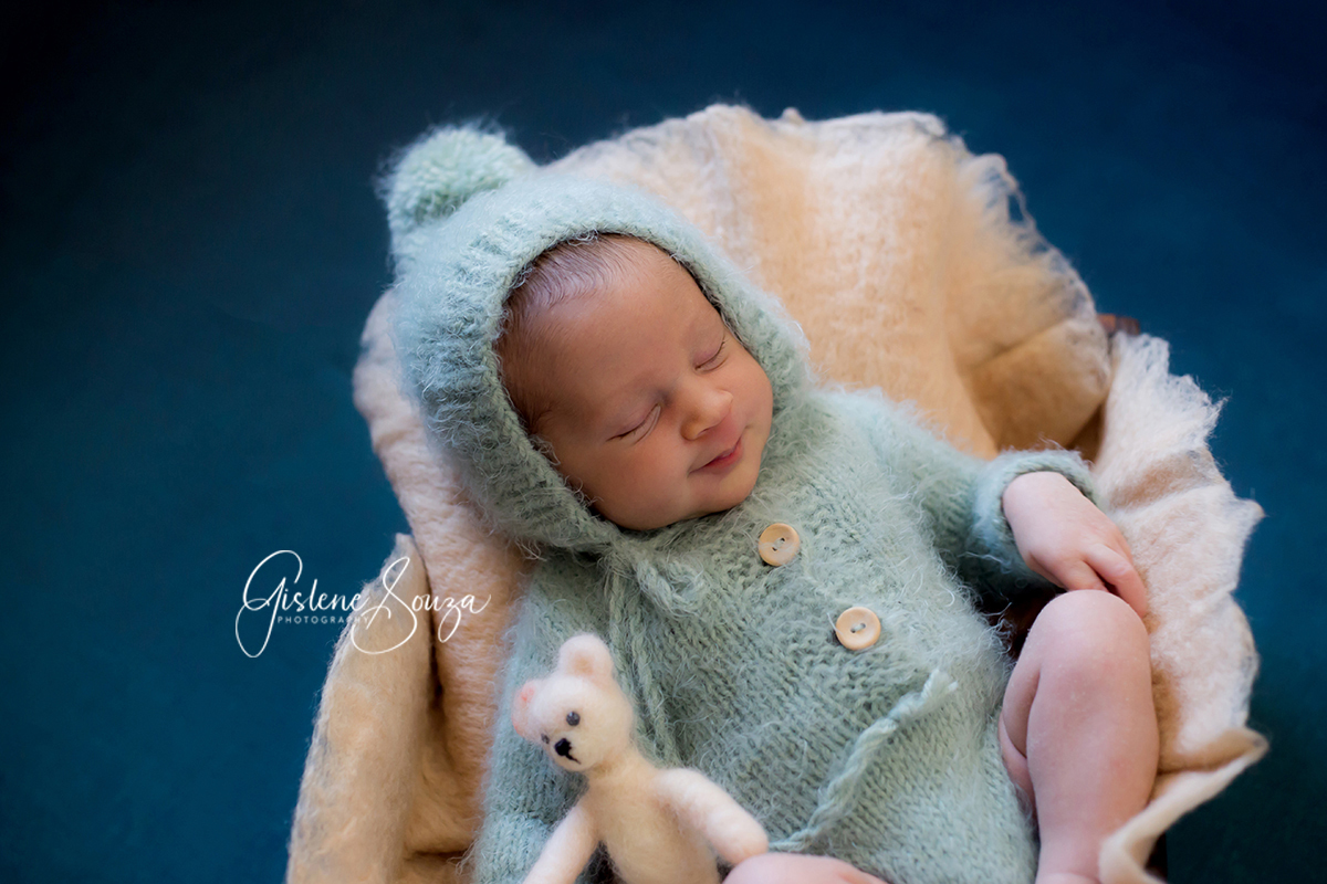 Fotografia de newborn em Belo Horizonte pose no prop. Newborn com ursinho e piso verde.