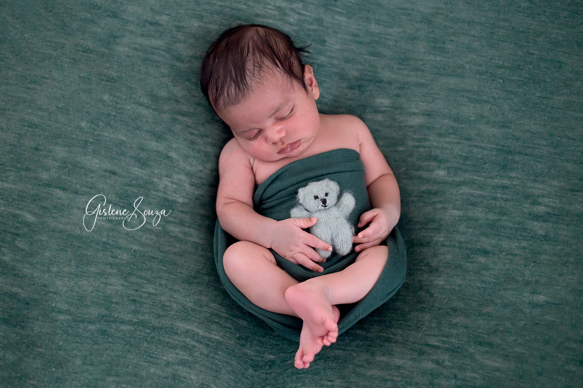 Fotografia de newborn, recém nascido na cidade de Belo Horizonte. Ensaio de newborn no puff de barriguinha para cima com ursinho.