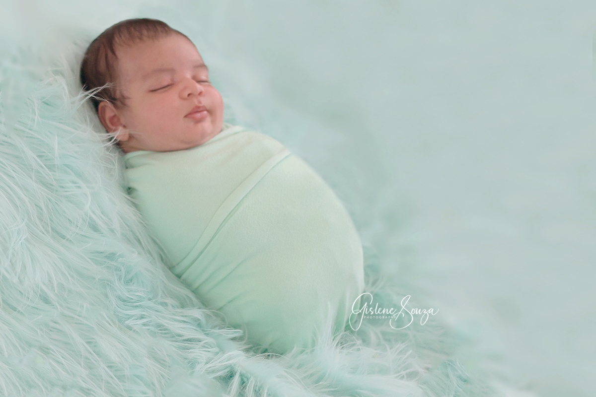 Fotografia de recém-nascido em Belo Horizonte. Ensaio newborn no pelo sobre o puff. Bebê enrolado no wrap. composição em verde.