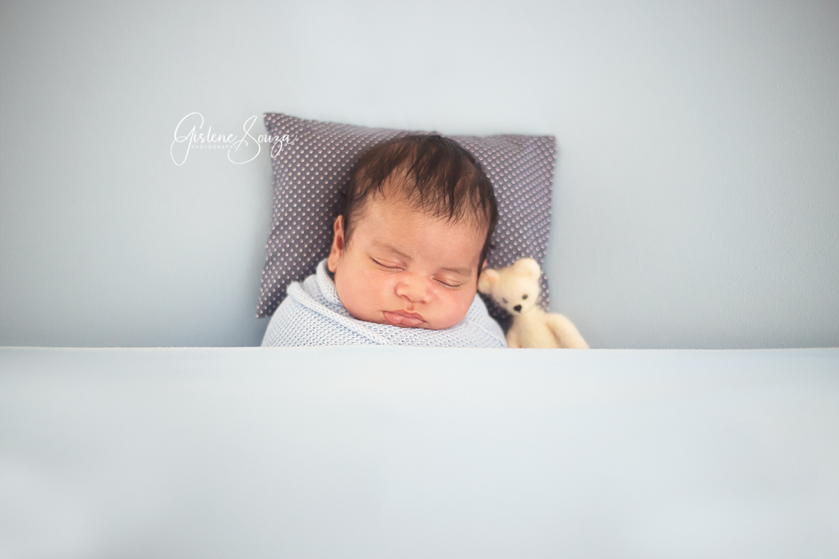 Ensaio fotográfico de newborn na cidade de Belo Horizonte. Pose no puff de barriga para cima com ursinho. 