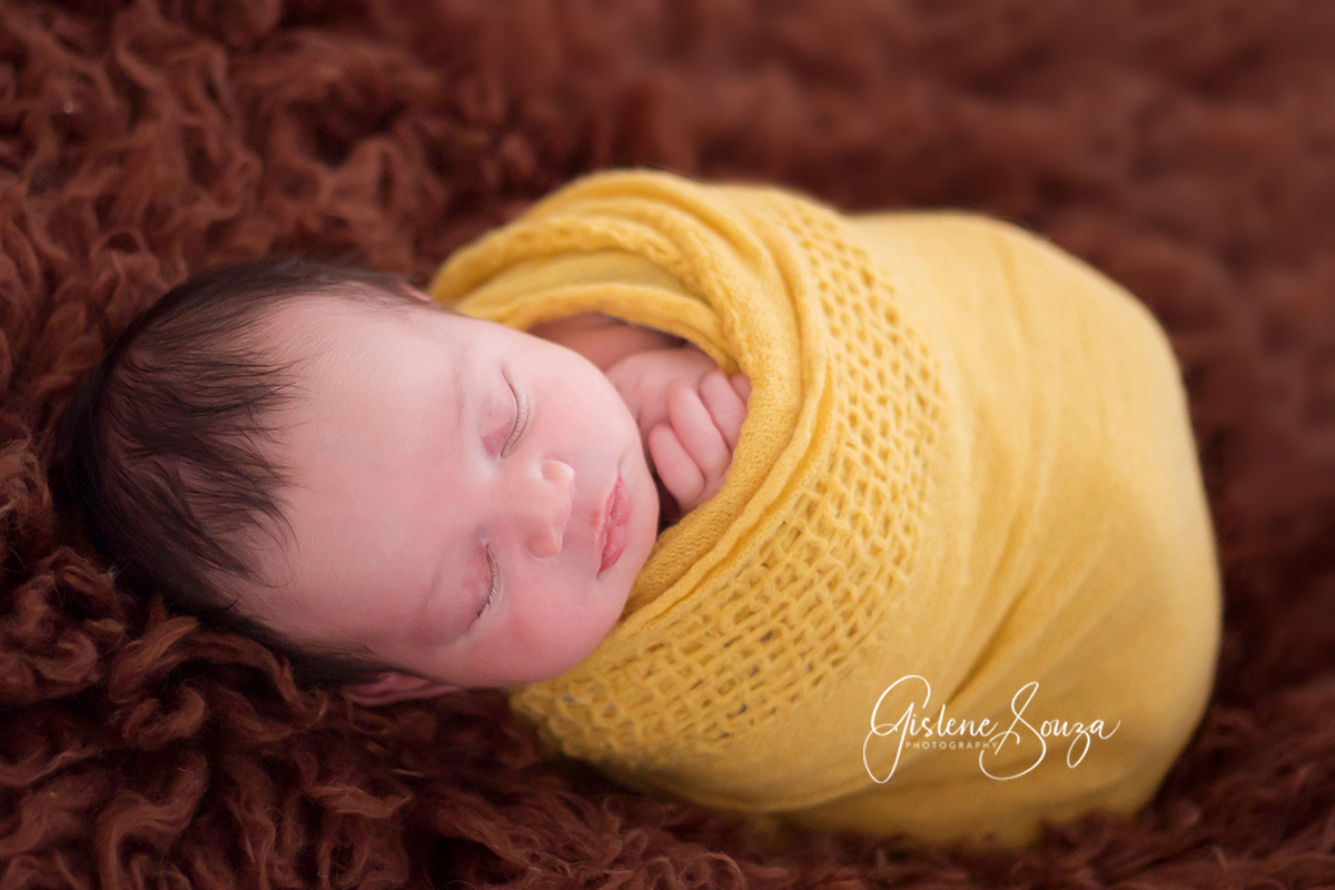 Ensaio de newborn em Belo Horizonte. Foto de recém nascido no puff enrolado no puff. Composição de contrate marrom e amarelo.
