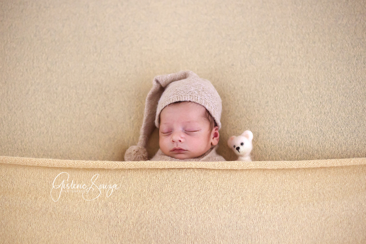 Ensaio de recém nascido - newborn em estúdio em Belo Horizonte. Pose de barriguinha para cima no puff, com touca soneca e ursinho.