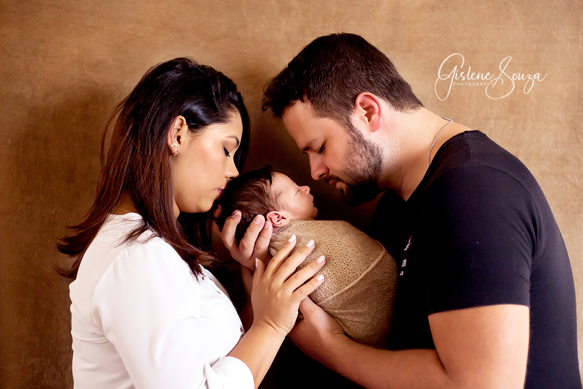 Fotografia de newborn - recém nascido. Pose com os pais, bebê enroladinho no .rap. Realizado em Pará de Minase.