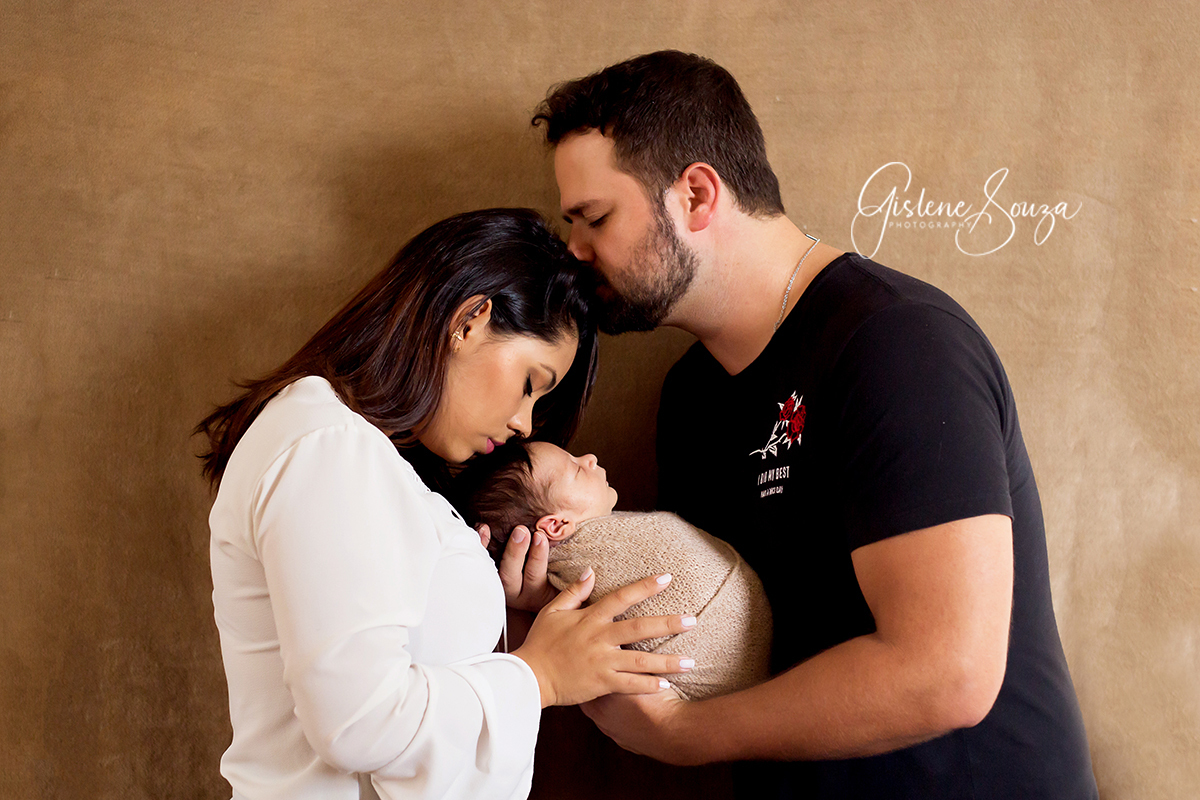 Fotografia de recém nascidos em estúdio em Pará de Minas. Fotografia com os pais. Menino enrolado  no wrap.