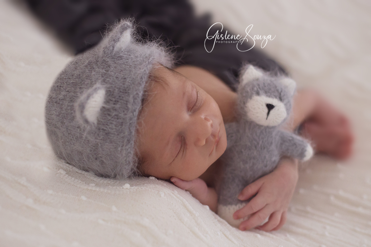 Fotografia de recém nascido em estúdio em Pará de Minas. Pose no puff de ladinho, com touca de gatinho e gatinho. 