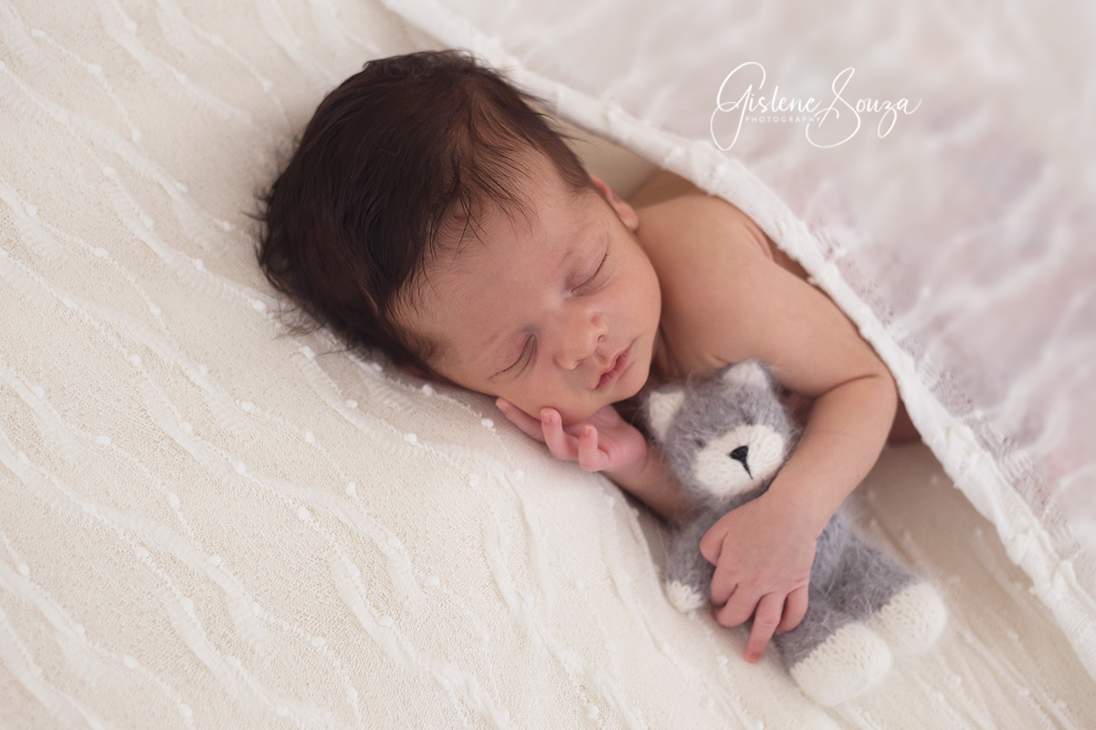 Fotografia de Newborn em Pará de Minas. Newborn de menino no puff de ladinho com gatinhao.