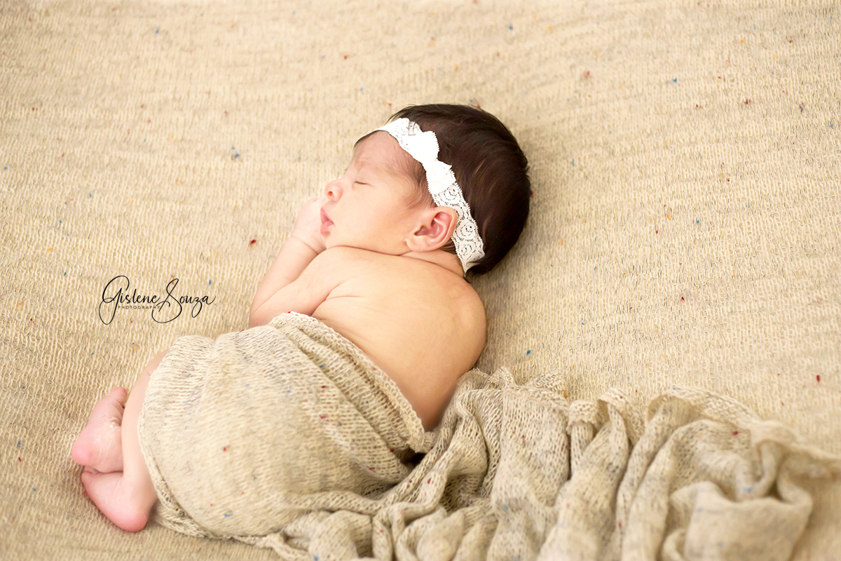 Fotografia de newborn em Belo Horizonte. Bebê posicionada do puff com manta e wrap do mesmo tecido. Newborn Menina.