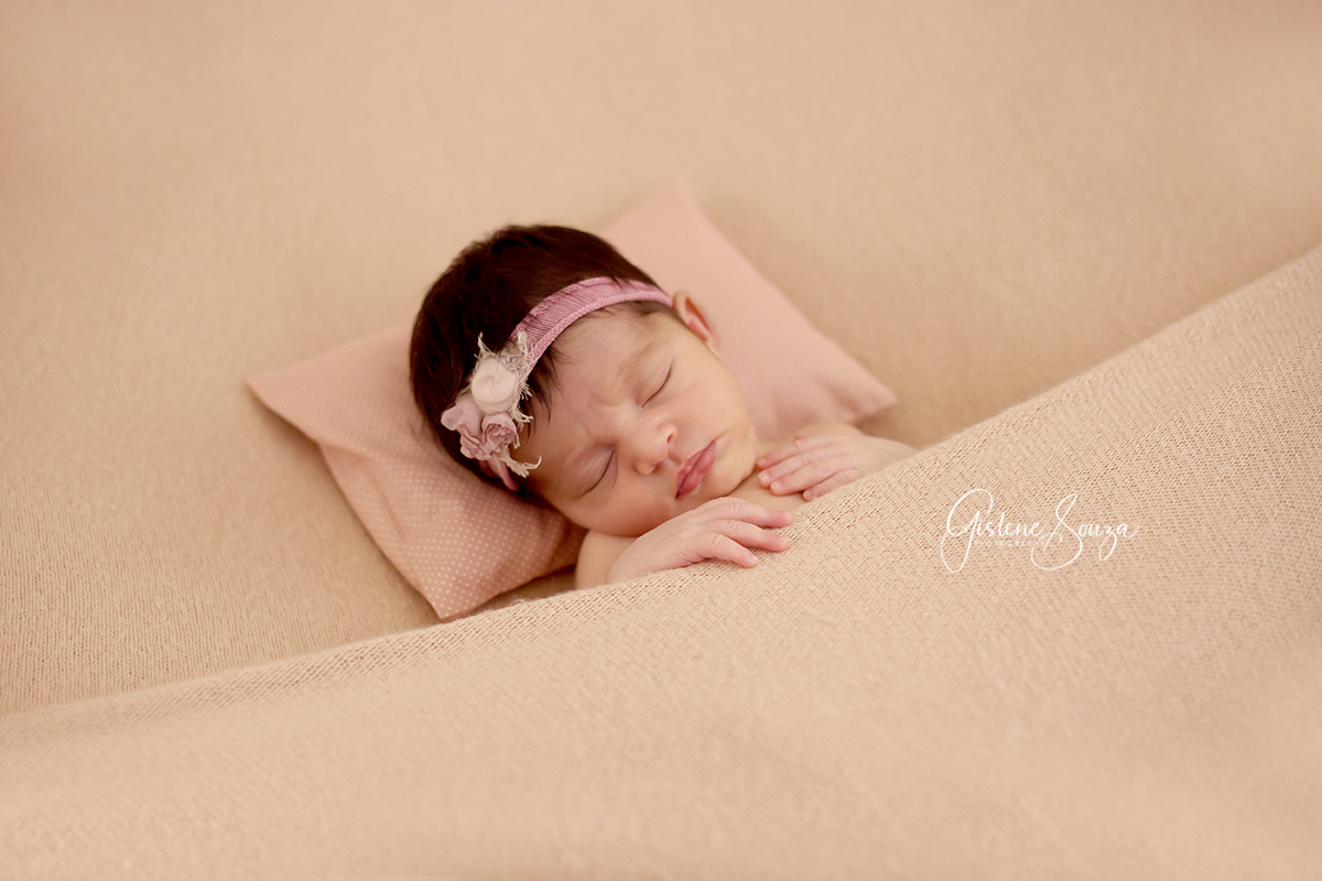 Fotografia de Newborn em Belo Horizonte em estúdio. Foto de menina, pose no puff nos tons de rosa. Puff barriguinha para cima.