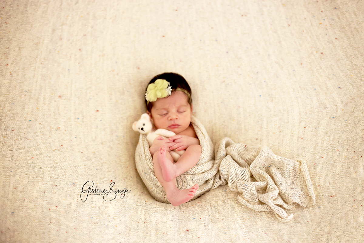 Foto Newborn. Menina enrola no wrap. Pose sobre o puff, com manta e wrap iguais, mesma cor. Ensaio em Belo Horizonte.