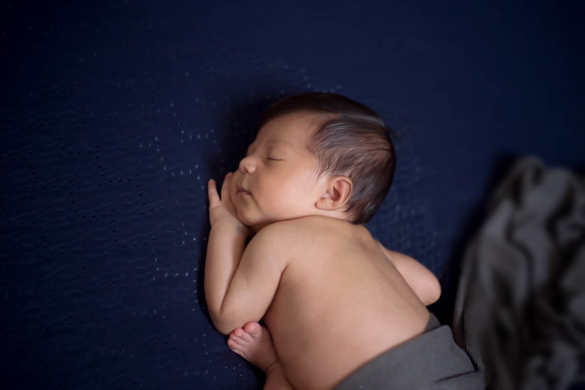 Fotografia newborn em Para de Minas. Pose no puff com composição em azul escuro.