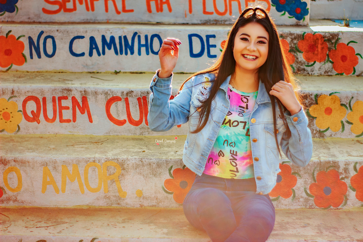 Fotografia de menina sentada em uma escada sorrindo em ensaio realizado na cidade de Caçapava do Sul, Rio Grande do Sul