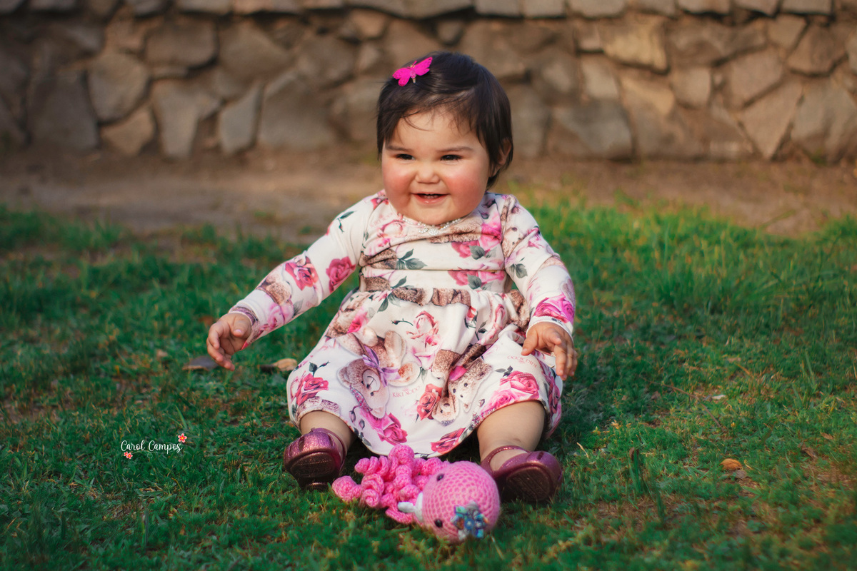 Fotografia de menina de 1 aninho sorrindo olhando para o lado em ensaio realizado em Caçapava do Sul, RS