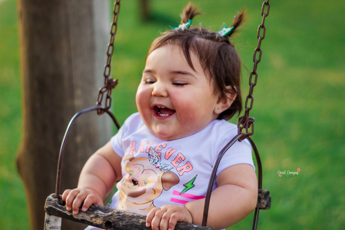 Fotografia de menina de 1 aninho sorrindo olhando para a frente em ensaio realizado em Caçapava do Sul, RS