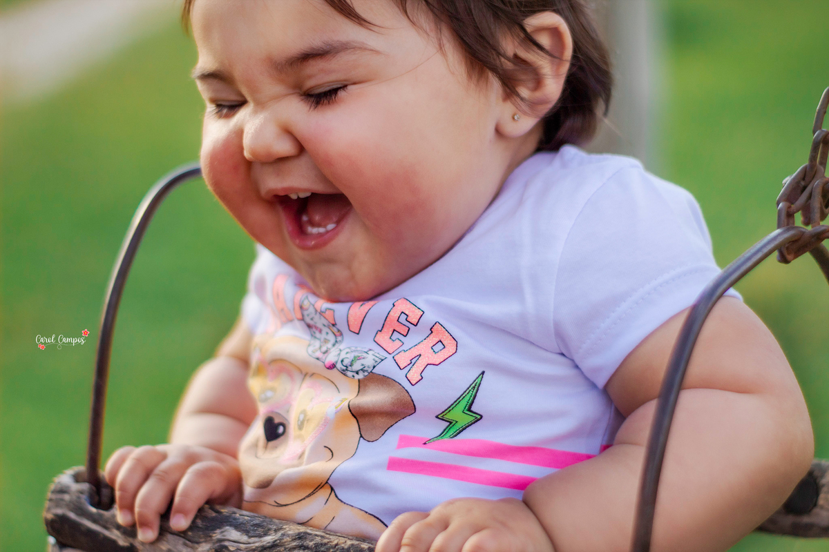 Fotografia de menina de 1 aninho dando gargalhada em ensaio realizado em Caçapava do Sul, RS