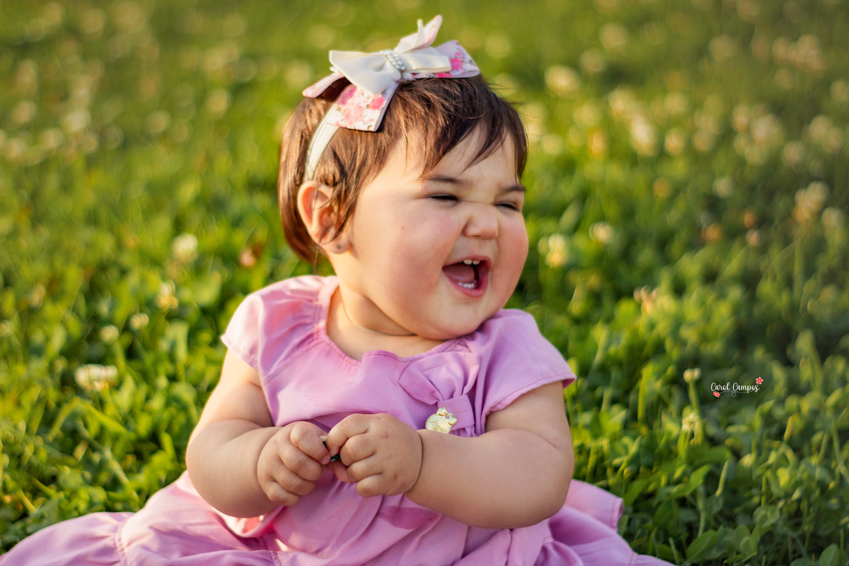 Fotografia de menina de 1 aninho sorrindo olhando para o lado em ensaio realizado em Caçapava do Sul, RS