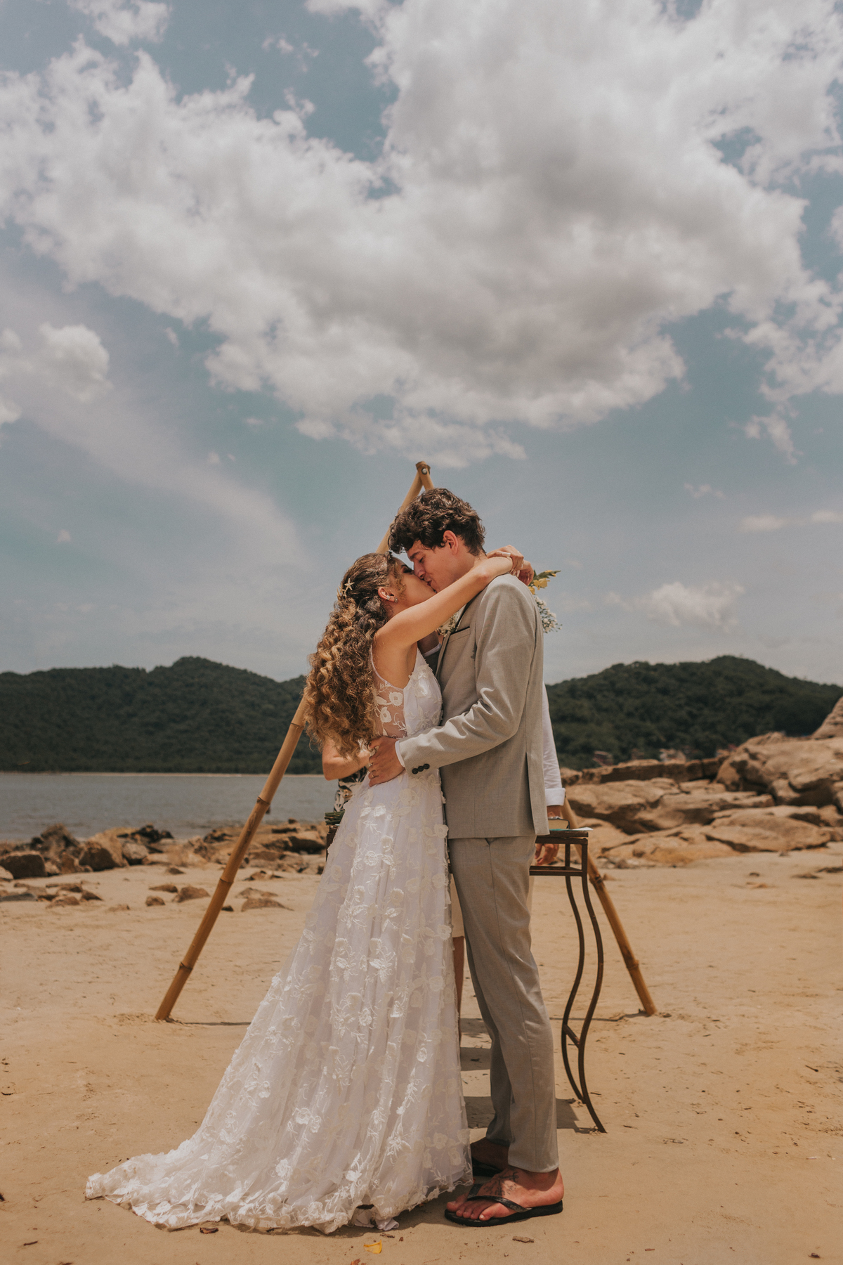 momento do beijo dos noivos em casamento de dia na praia de são vicente