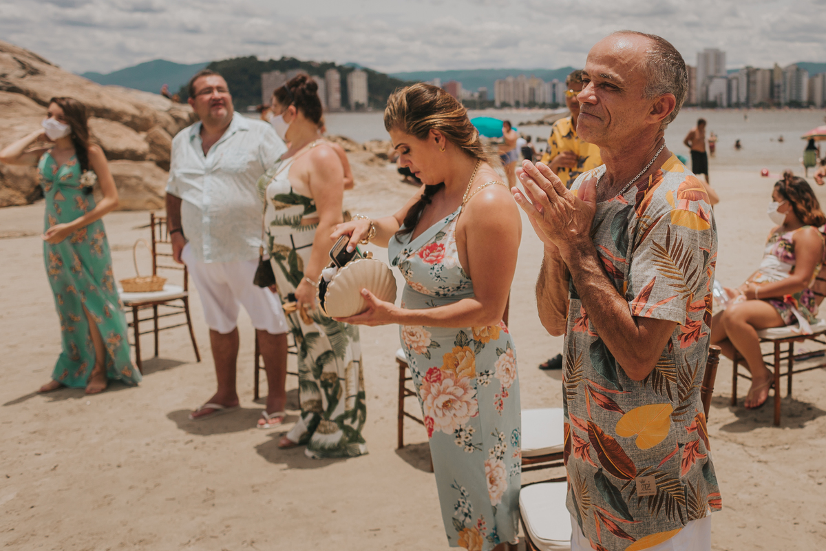 convidados e pais dos noivos aplaudindo beijo em casamento minimalista na praia de são vicente