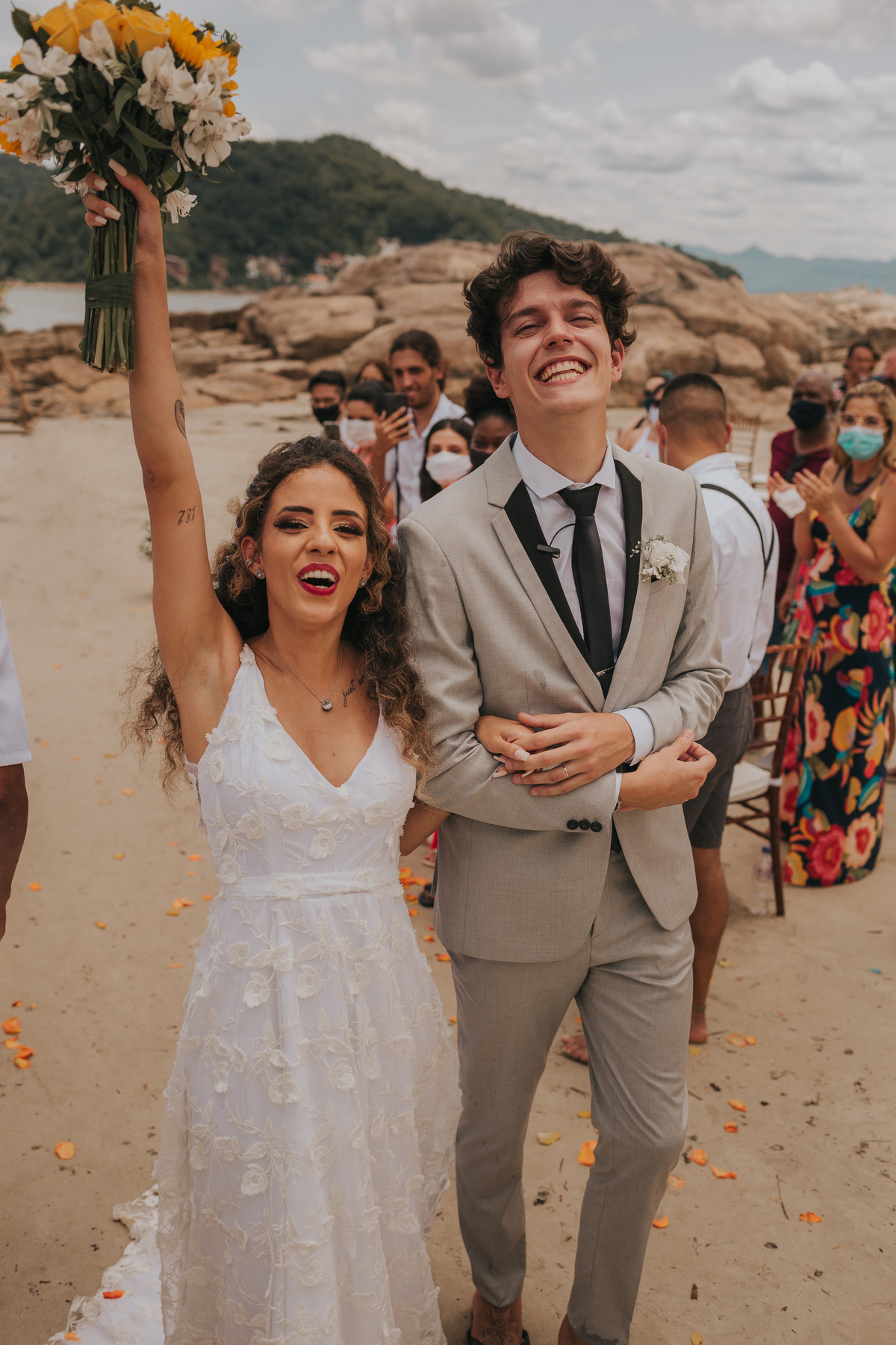 comemoração dos noivos na saida no fim da cerimonia em casamento na praia de dia em são vicente, baixada santista