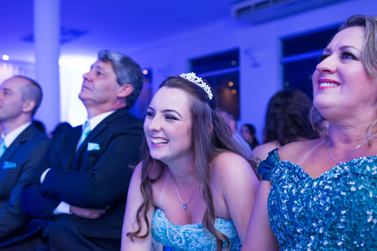 aniversariante rindo ao ver a retrospectiva em festa de debutante