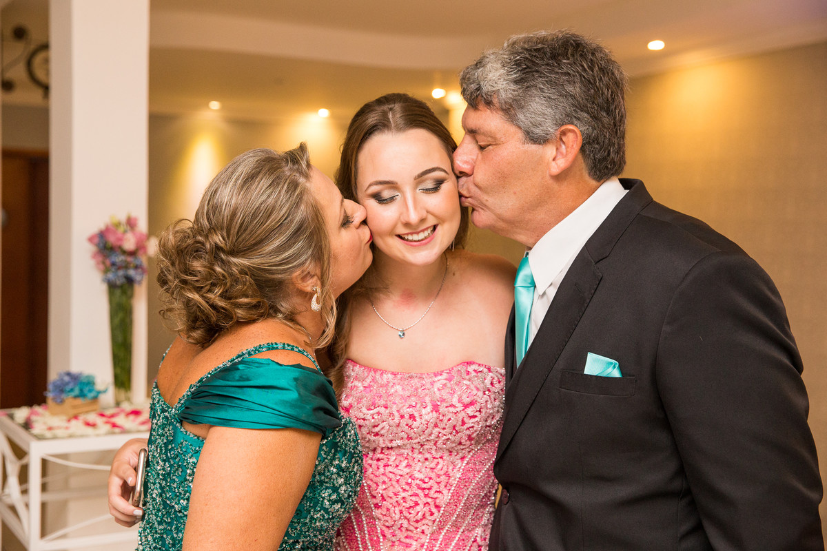 mãe e pai beijando filha debutante