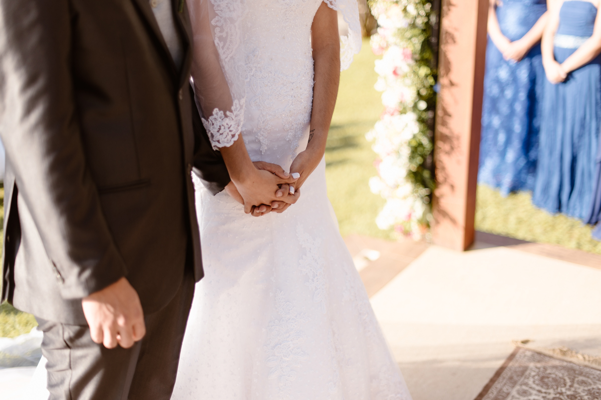 Detalhes das mãos dos noivos conectadas durante a cerimônia