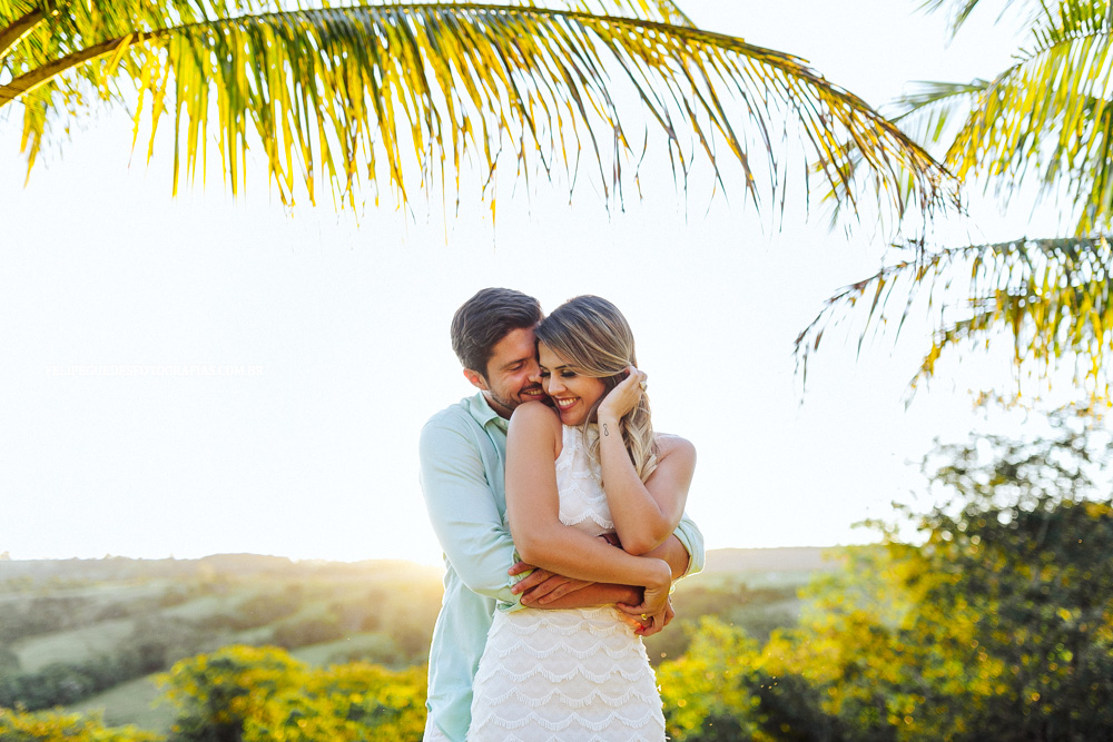 casal abraçado sorrindo perto de coqueiro