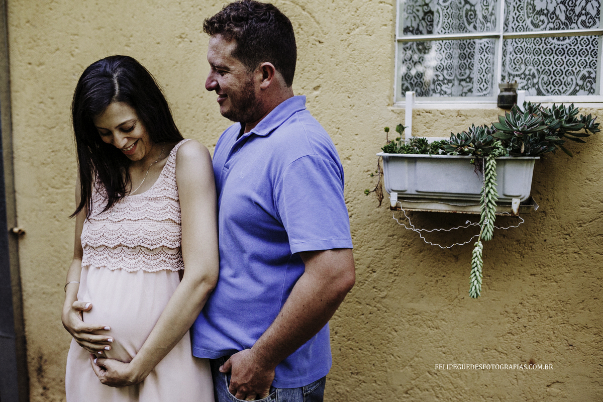 casal sorri olhando seu bebê na barriga