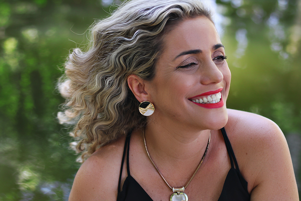 melhores-fotos-ensaio-feminino-winnie-rosa-fotografia-ensaios-rj-fotos-diferentes-quarenta anos-melhores-fotos-feminina-jardim-fotografa-retrato-winnie-rosa-fotos-galeria de arte-barra-mansa-criativa-mulher sentada em frente ao lago com cabelos ao vento