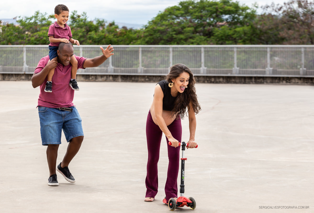 Ensaio divertido de gestante. Família brincando de patinete. Fotografia espontânea em Belo Horizonte. BH.