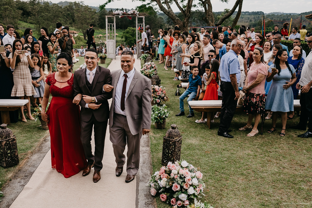 Fotografia de casamento entrada do noivo noivo sorrindo casar no campo casamento de dia noivo com os pais casamento ao ar livre fotografia documental por caio henrique sao paulo fotografo de casamento