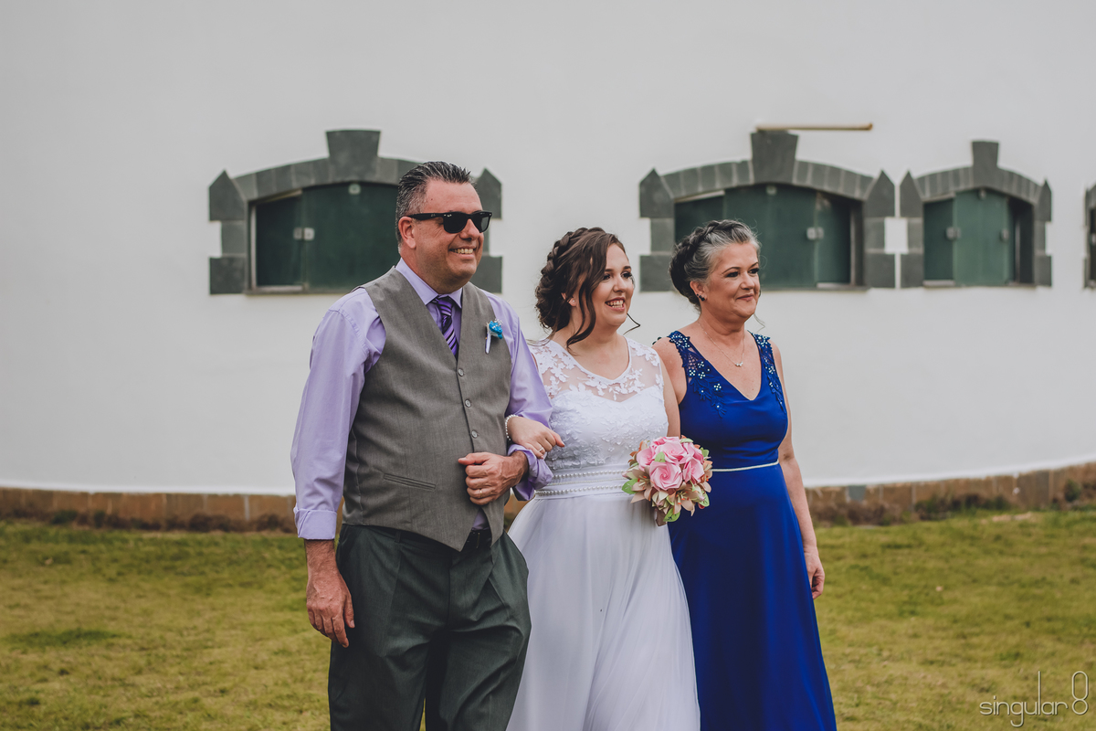 noiva-entrando-com-pai-e-mãe-noiva-de-vestido-simples-com-renda-penteado-com-flores-naturais-bouquet-de-papel-mãe-da-noiva-com-vestido-azul-royal-pai-da-noiva-com-óculos-escuro-casamento-de-dia-sitio-ibiuna-são-paulo