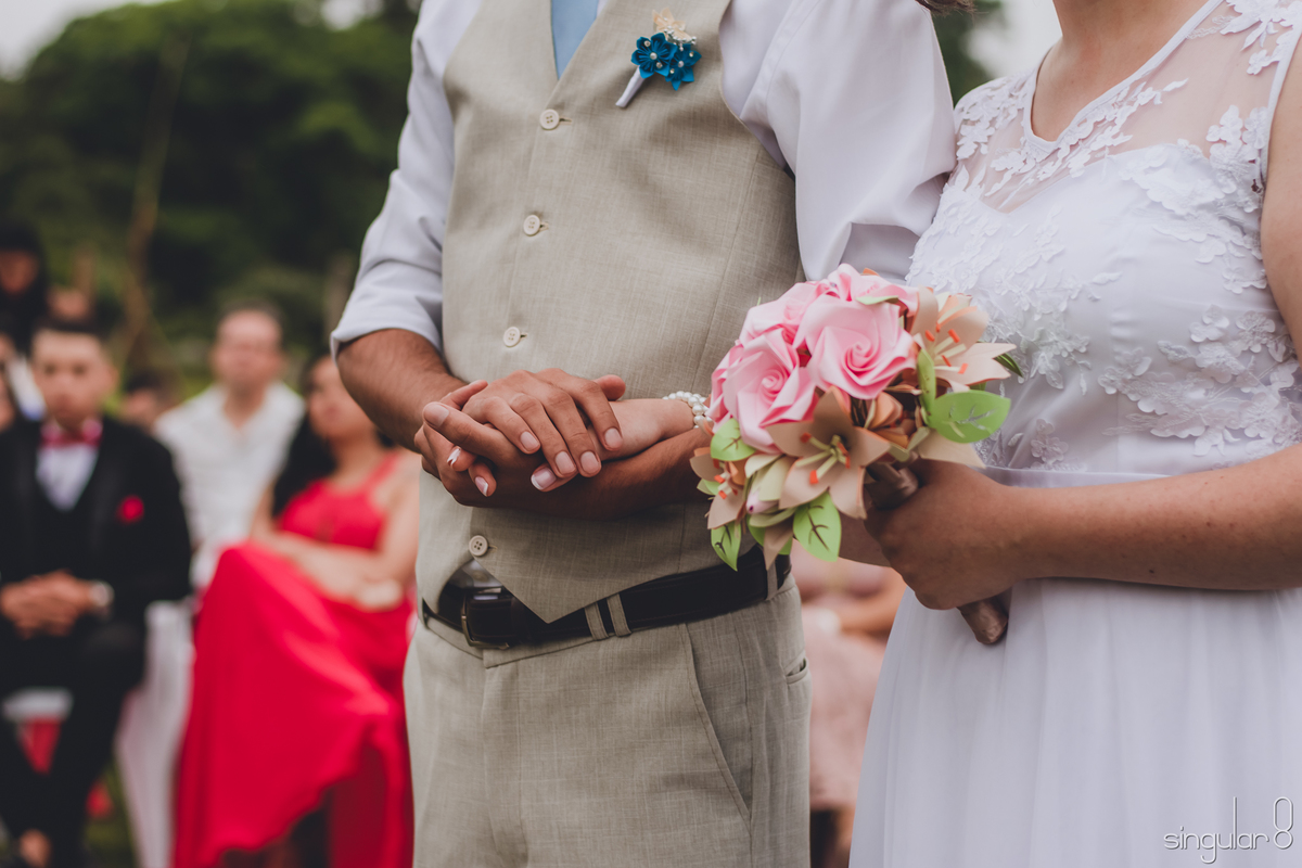 noivos-de-mãos-dadas-durante-cerimônia-religiosa-casamento-de-dia-sitio-ibiuna-noiva-com-bouquet-de-papel