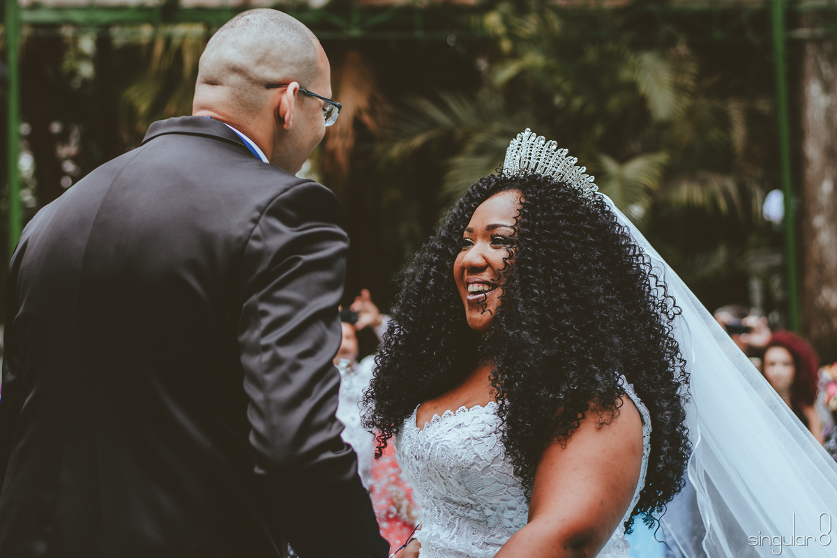 noiva negra e cacheada emocionada na entrada do casamento