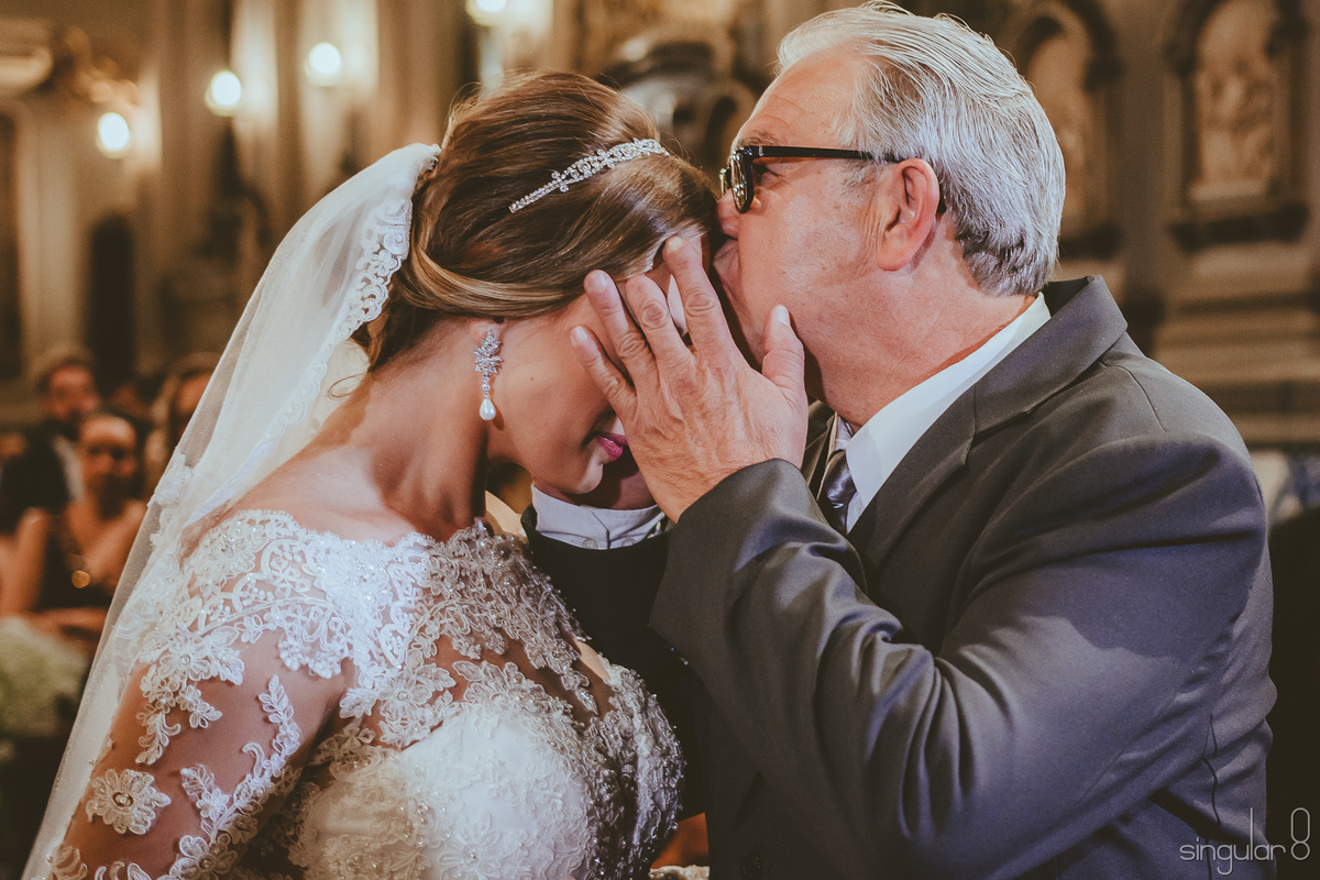 Fotografia do pai beijando a noiva em casamento na Capela da Puc Perdizes