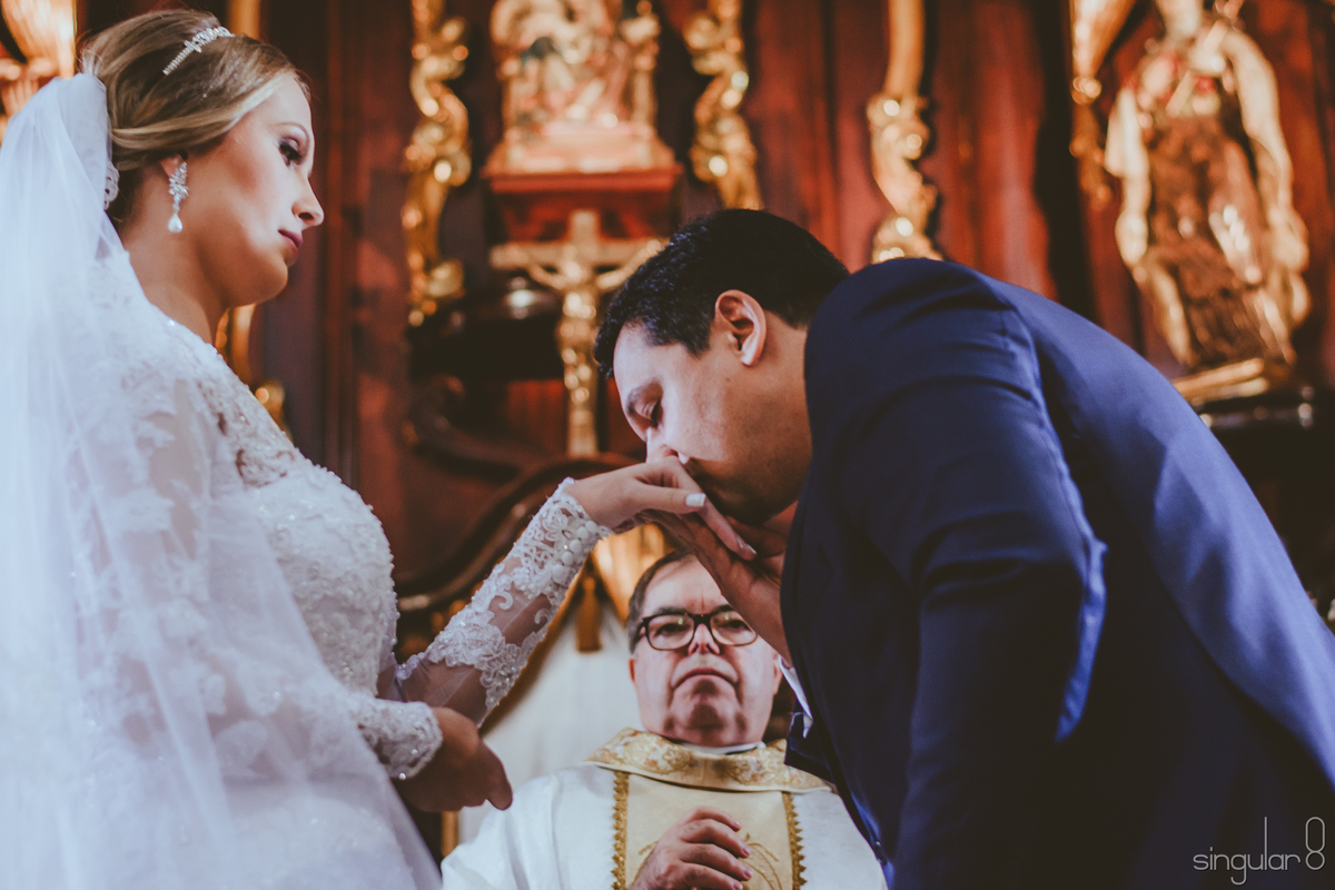 Noivo beijando a mão da noiva depois de colocar a aliança em casamento na Capela da Puc São Paulo Perdizes