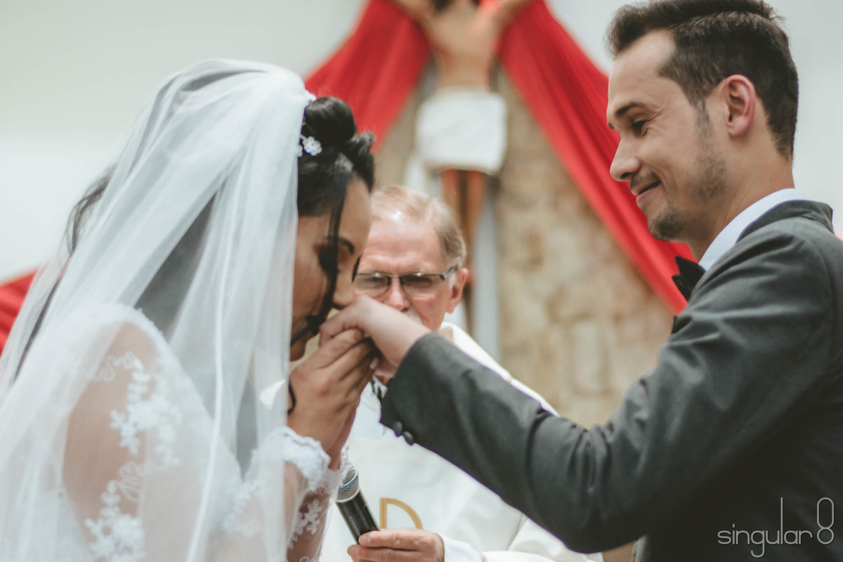 Noiva beijando a mão do noivo na cerimônia religiosa da Igreja
