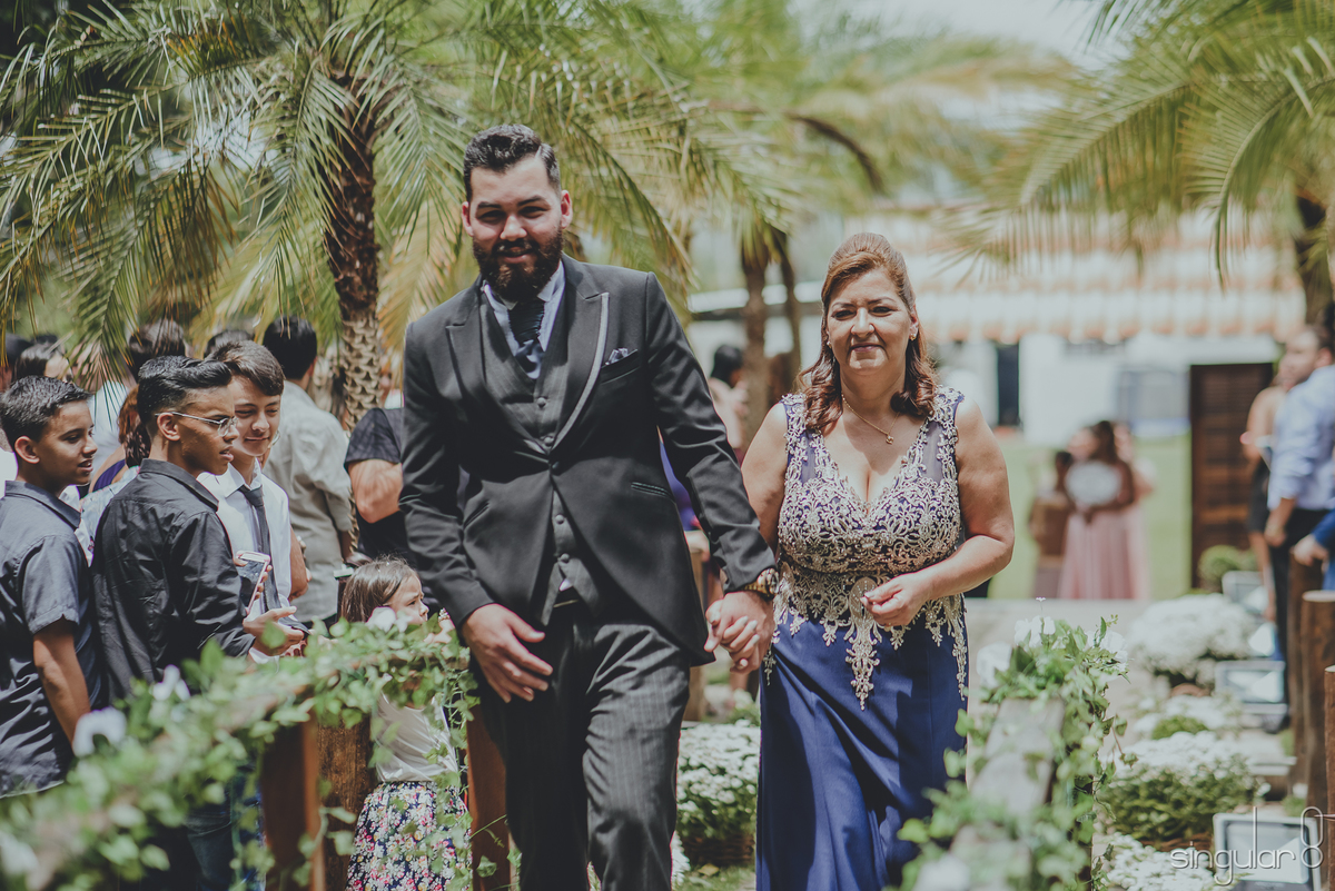 entrada do noivo com terno preto e mãe com vestido azul