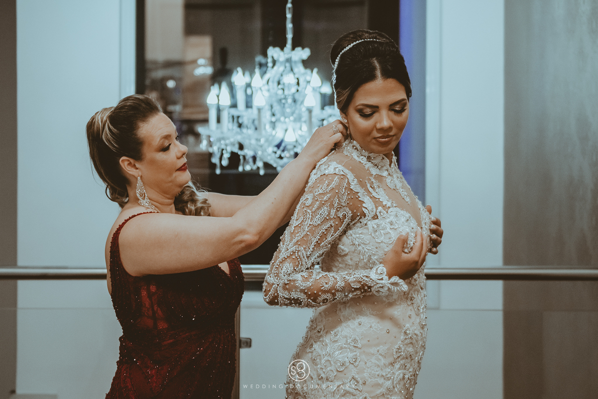 fotografia da mãe fechando o vestido da noiva em casamento de Alphaville
