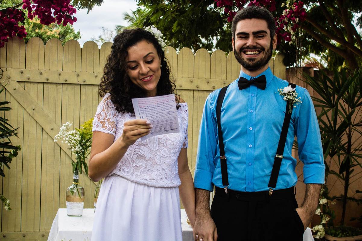 fotografia dos noivos, noiva lendo os votos enquanto o noivo sorri durante casamento realizado na cidade de Jampruca, Minas Gerais