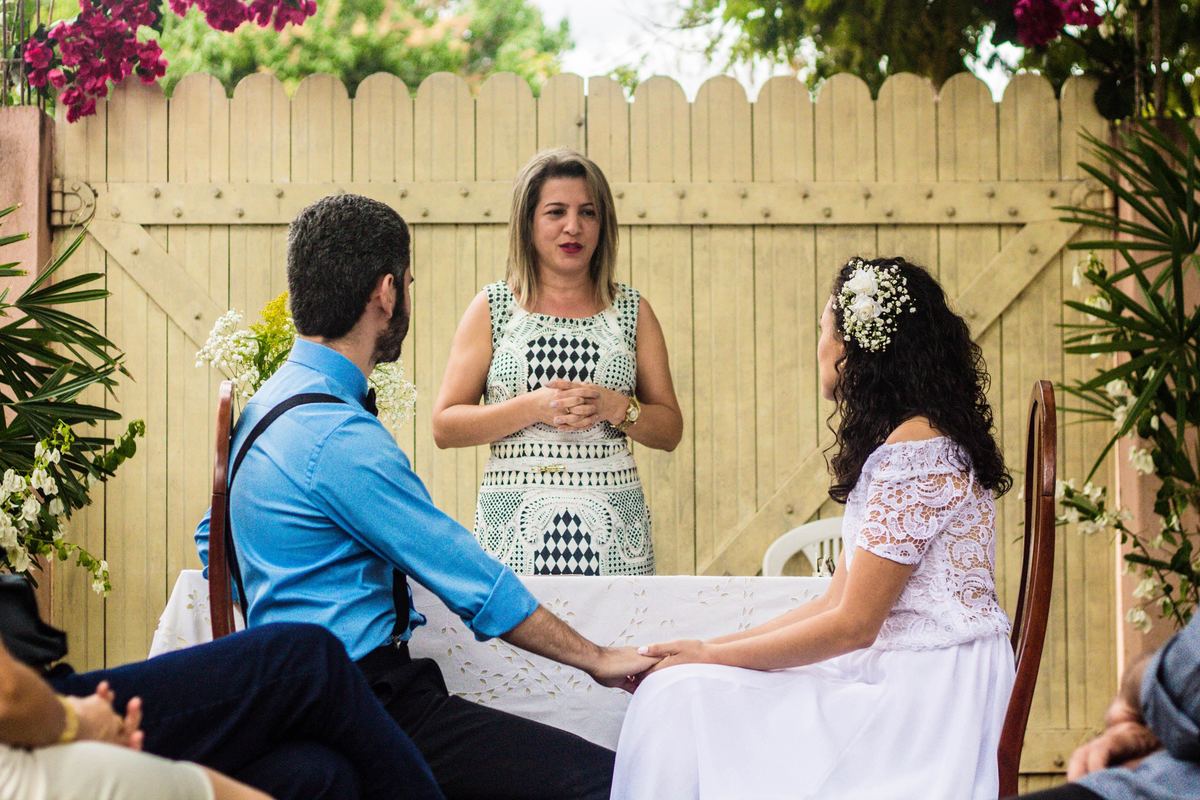 fotografia dos noivos de mãos dadas olhando para a celebrante em casamento realizado na cidade de Jampruca, Minas Gerais