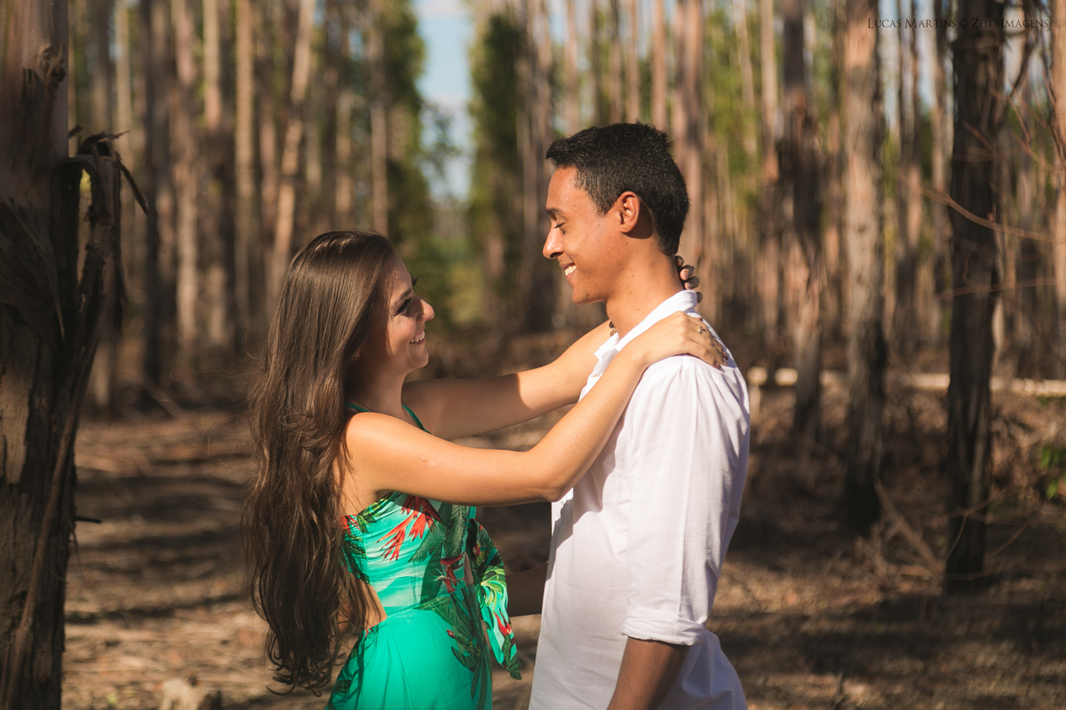 casal posa na estrada com plantacao de eucalipto