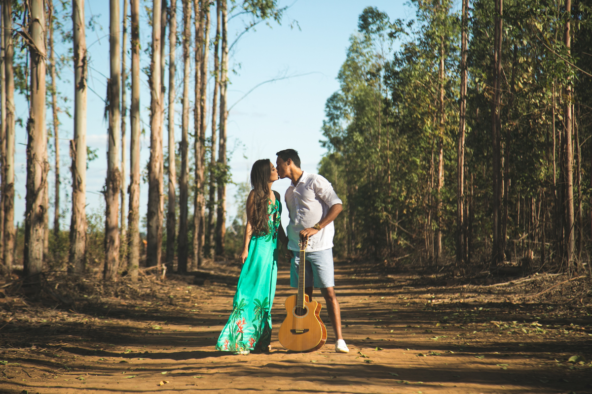 casal posa na plantacao de eucalipto com violao