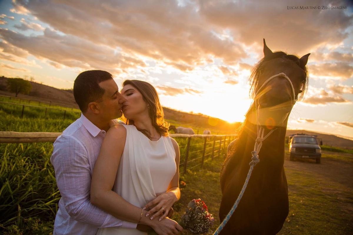 casal posando com o cavalo no por do sol dourado

