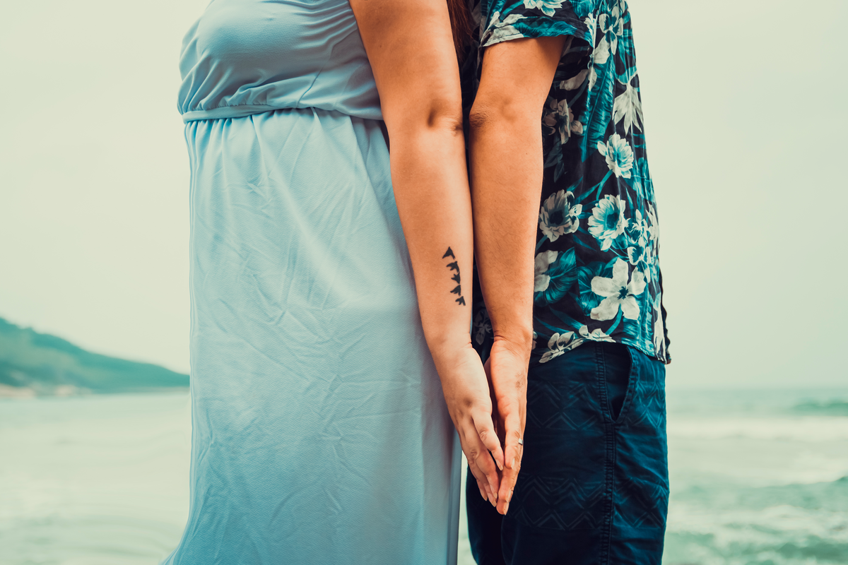 fotografia do casal de costas um para o outro encostando as mãos, próximo ao mar, em ensaio fotográfico na praia de grumari, Rio de Janeiro - RJ 