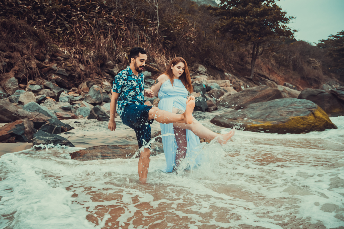 fotografia do casal chutando as ondas durante ensaio fotográfico de casal realizado na praia de Grumari, Rio de Janeiro