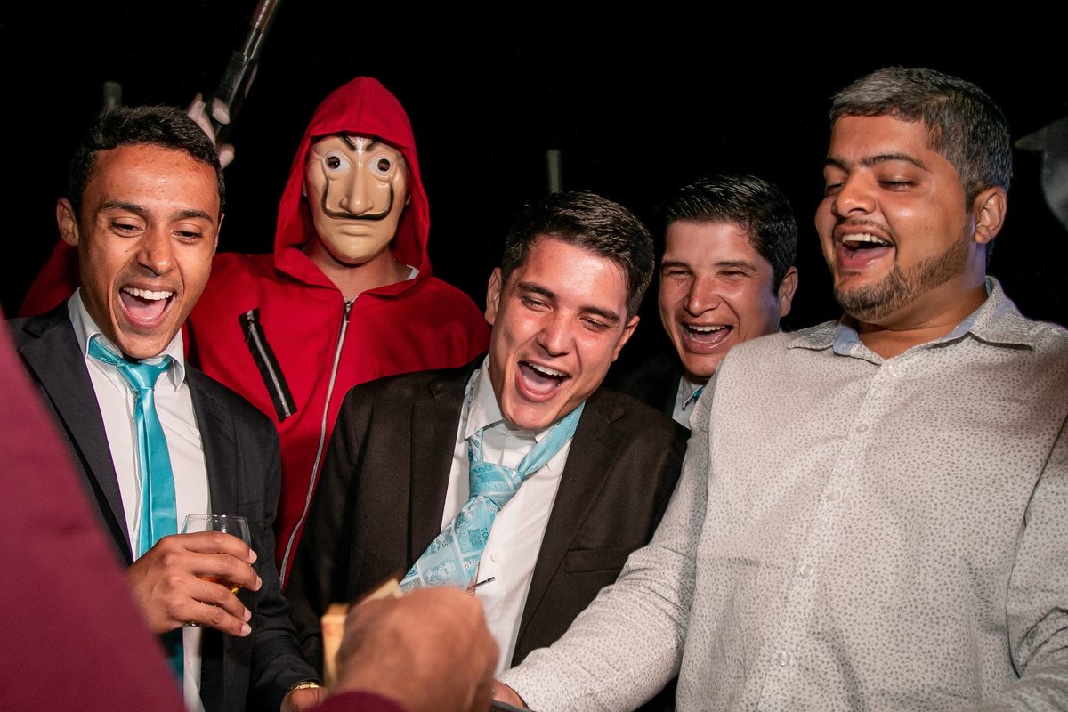 fotografia do corte da gravata, o noivo e amigos comemorando junto de um convidado vestido de personagem de 