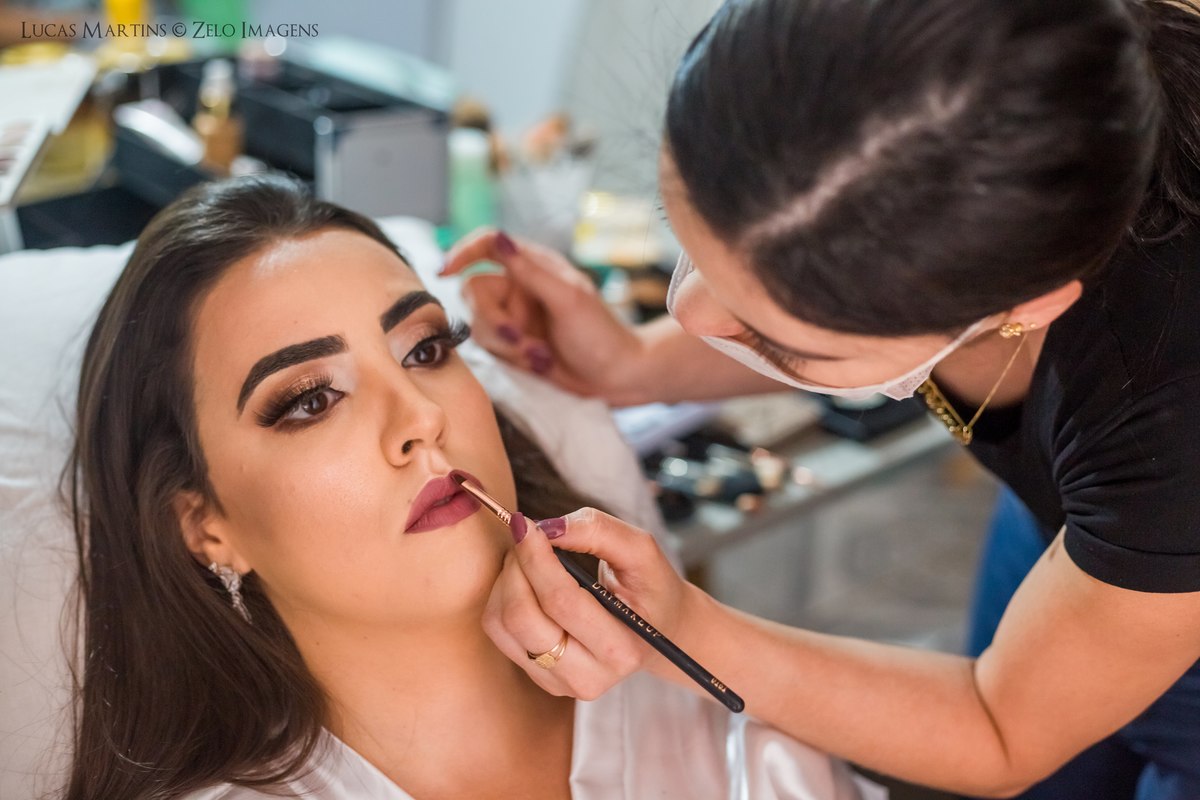 fotografia da maquiagem, maquiadora passando o batom na noiva, durante o making of de casamento realizado na cidade de Virgem da Lapa - MG. 