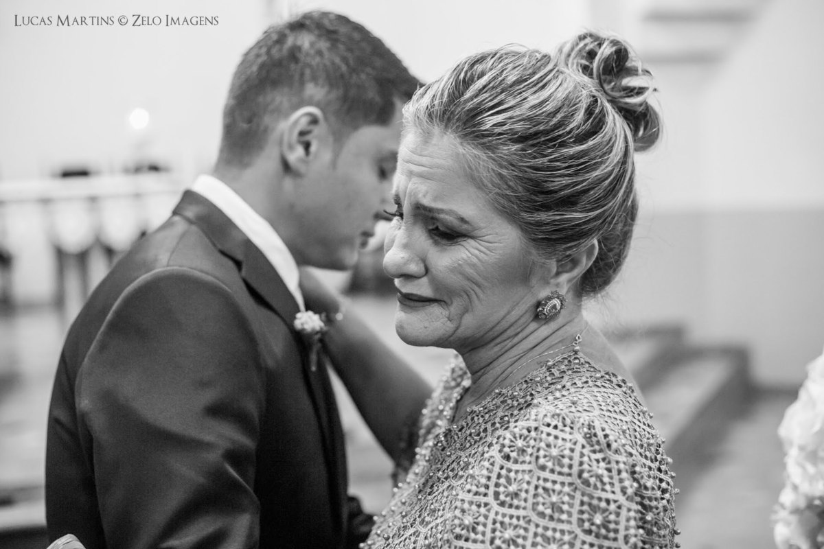 fotografia da mãe do noivo emocionada ao deixar seu filho no altar durante a cerimônia de casamento realizada em Virgem da Lapa, Minas Gerais.