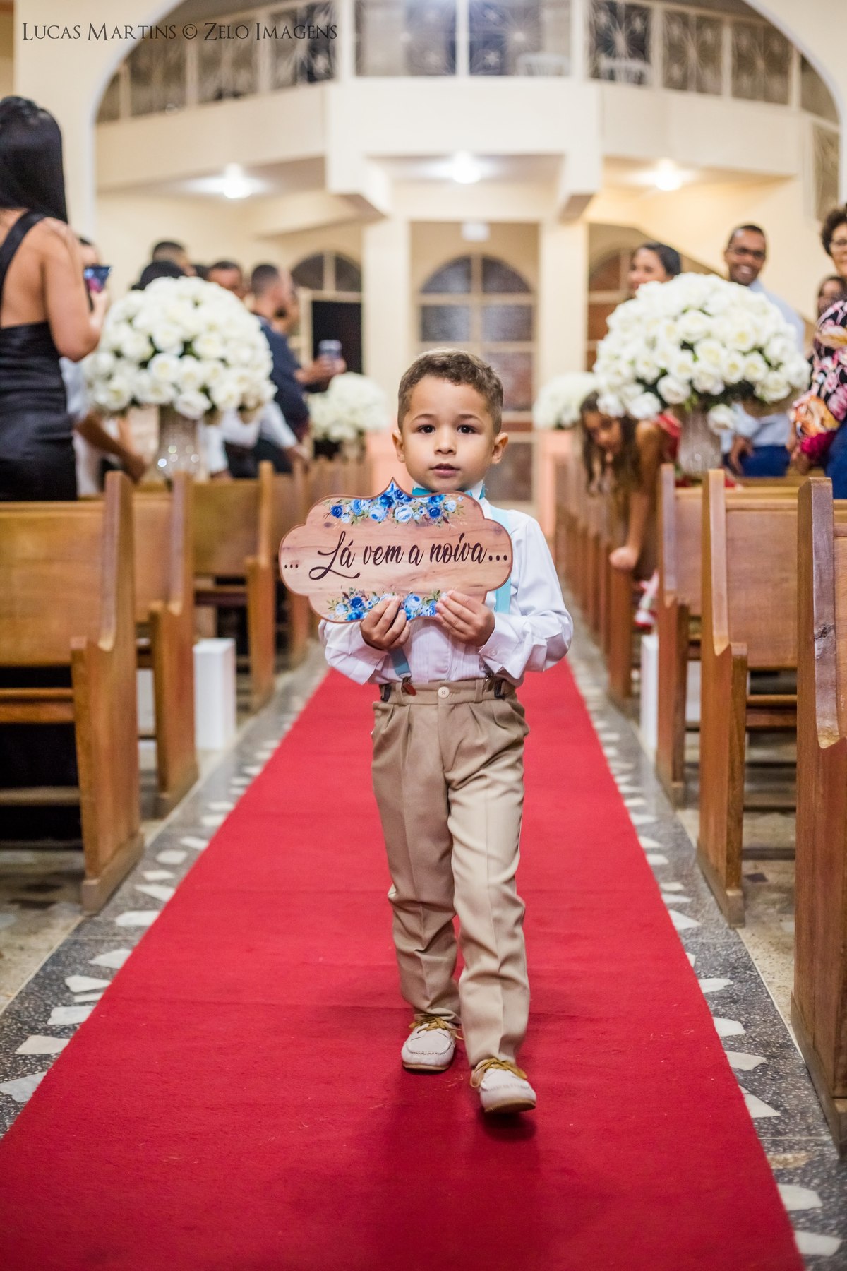 fotografia do pagem entrando com plaquinha de madeira, escrito 